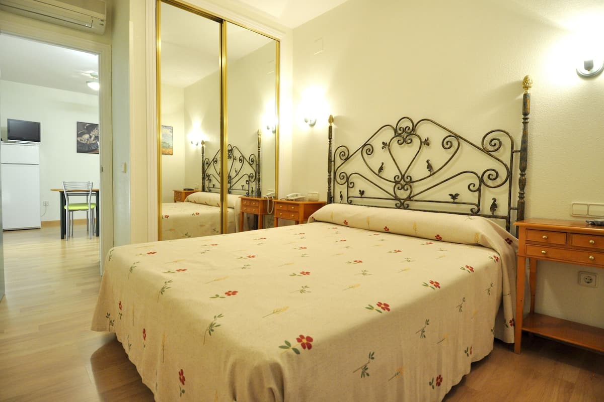 Ein Schlafzimmer mit einem Doppelbett, einem Spiegel, Nachttischen und einem Kleiderschrank.