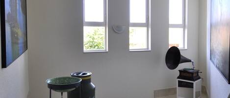 A stairwell with a green pitcher, a black speaker, and a window with a view of greenery.