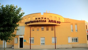 Un hôtel appelé « Apartamentos Arals » qui se distingue par sa façade incurvée, ses nombreuses fenêtres et son entrée dallée.