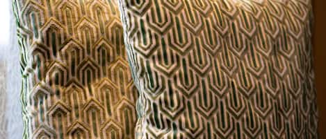 Two patterned pillows on a couch with a tablet on it.