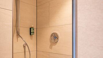 A shower with a handheld showerhead and a wall-mounted control panel.