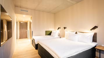 Ein Hotelzimmer mit zwei Betten, einem großen Spiegel und Holzboden.