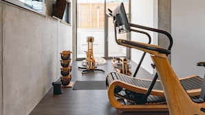 Un gimnasio moderno con equipo de ejercicio, ventanas amplias y un diseño minimalista.