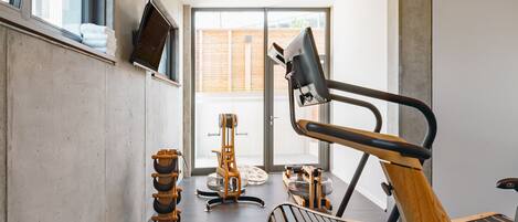Un gimnasio moderno con equipo de ejercicio, ventanas amplias y un diseño minimalista.