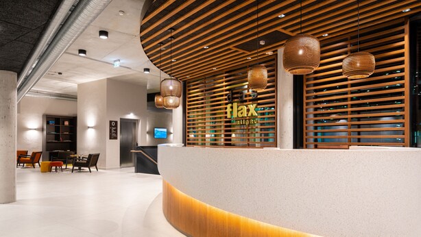 Un área de recepción con un mostrador curvo, listones de madera e iluminación colgante.
