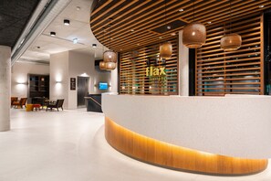 Un área de recepción con un mostrador curvo, listones de madera e iluminación colgante.
