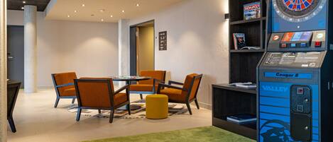 Una habitación con dardos, una mesa con sillas y una estantería.