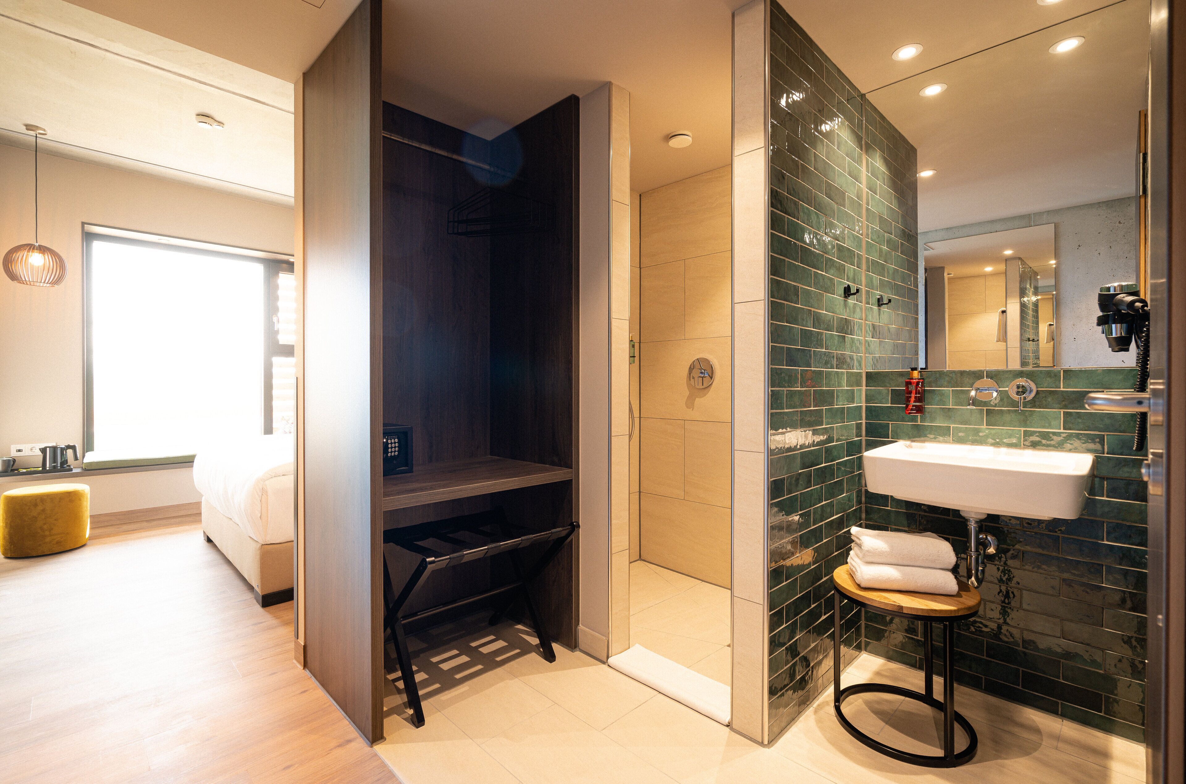 Une salle de bain moderne avec une douche à parois de verre, un lavabo avec une serviette et un tabouret en bois.