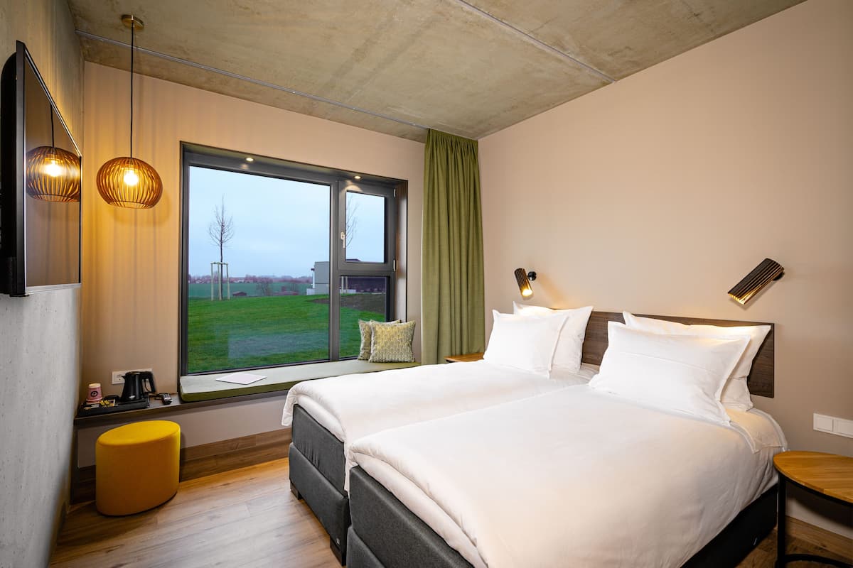 Una habitación de hotel moderna con una cama grande, un ventanal con vistas y una mesita.
