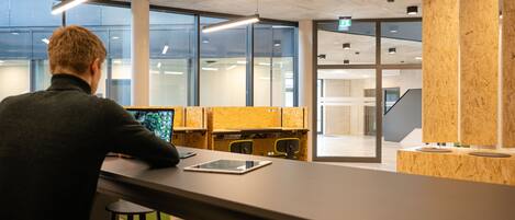 A modern office space with a person sitting at a desk, large windows, and a view of the interior.