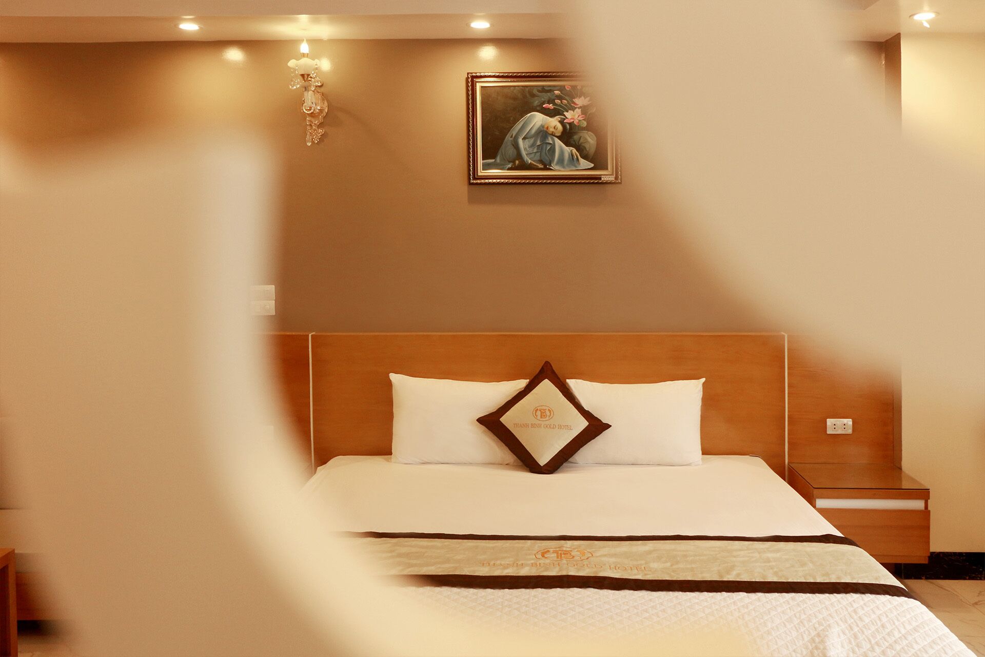 Ein Hotelzimmer mit hölzernem Kopfteil, einem Bett mit weißer Bettwäsche, einem Nachttisch und einem Wandbild.