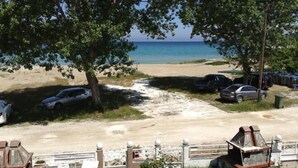 Un parking situé au bord de la plage, avec des voitures et un petit bâtiment.