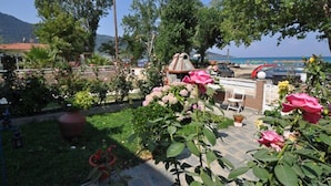 Un jardin agrémenté de plantes et de fleurs en pot, un barbecue et une vue sur la mer.
