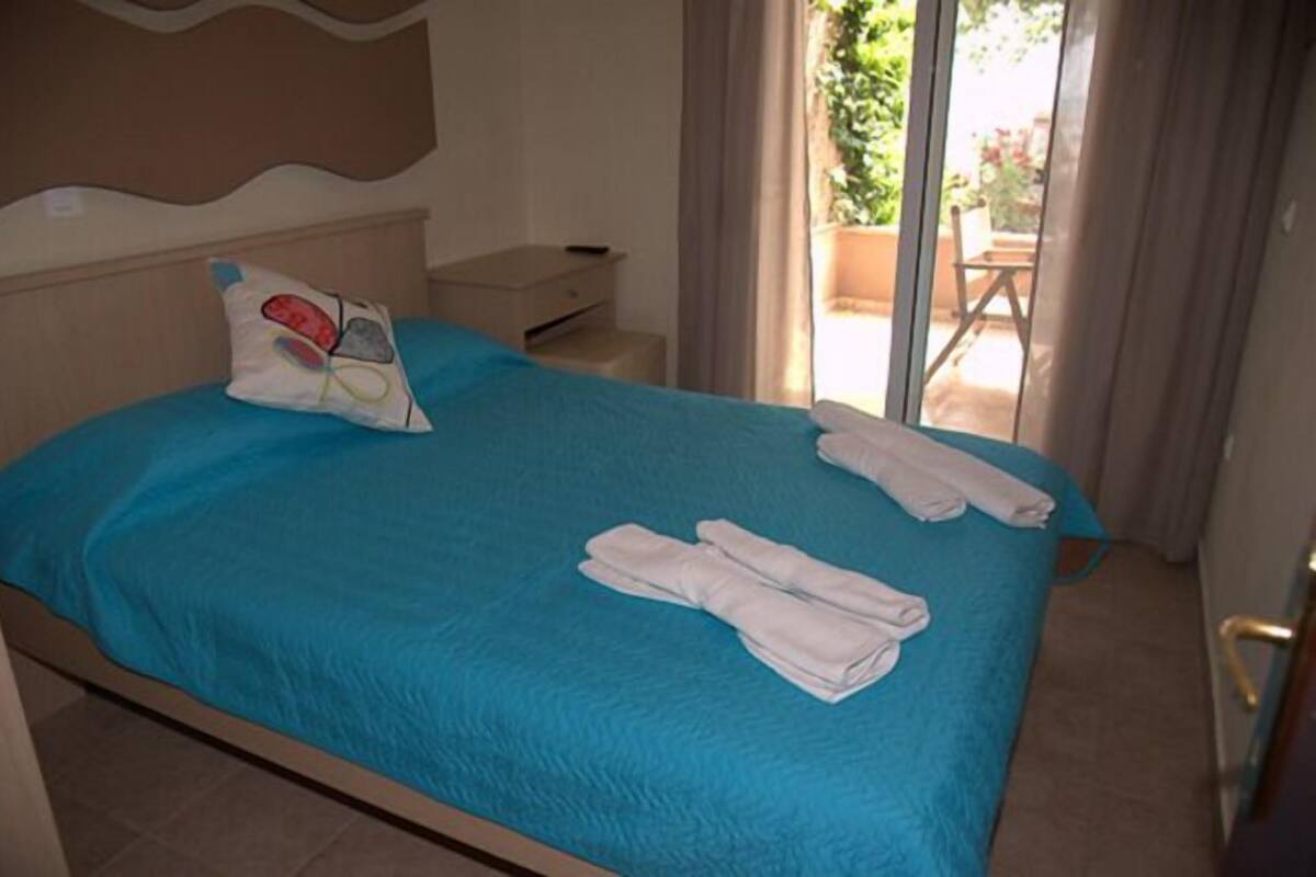 A hotel room with a bed, a pillow, and a set of towels.