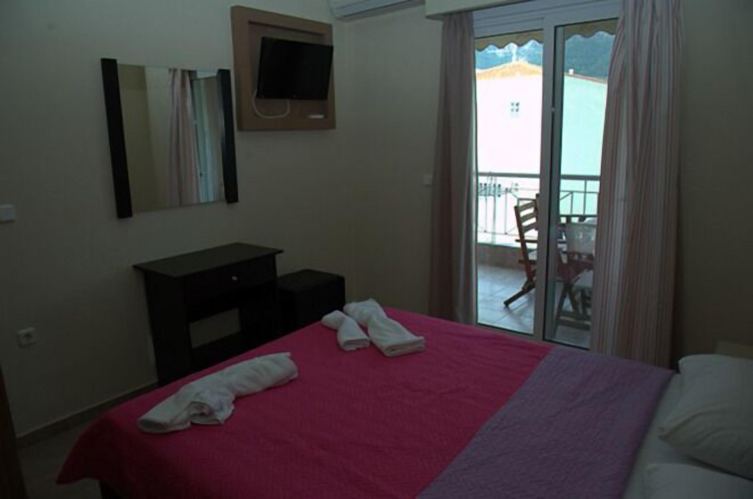 Ein Hotelzimmer mit einem Bett, einem Schreibtisch, einem Sessel, einem Fernseher und einem Balkon mit Blick.