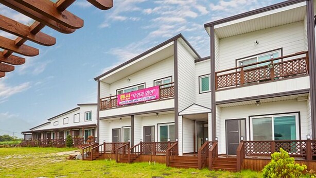 A multi-story residential building with a balcony and wooden deck. - Wuyeon and Inyeon Pension (Namhae)