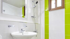A bathroom with a white sink, a mirror, a shower, and green tiles. - Wuyeon and Inyeon Pension (Namhae)