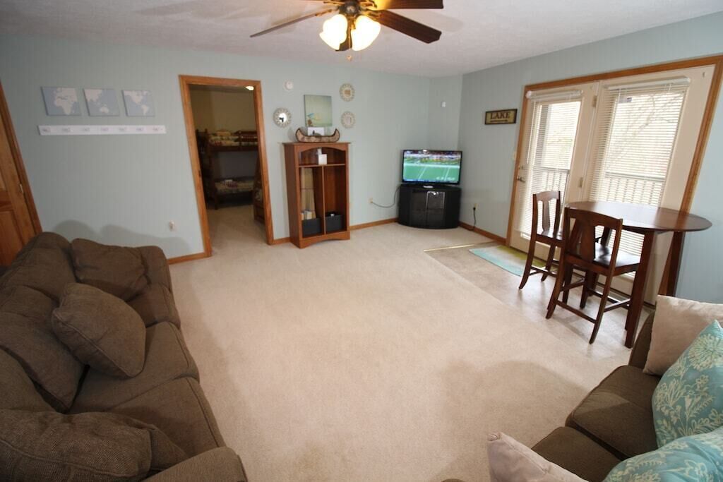 A living room with a brown couch, a television, and a dining table with chairs.