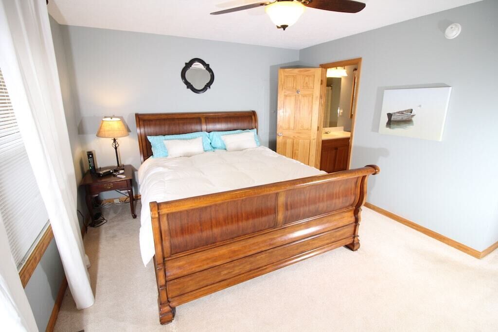 A bedroom with a wooden bed, a nightstand with a lamp, a wardrobe, and a mirror on the wall.