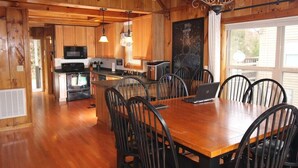 Un intérieur en bois comprenant une table et des chaises, un coin cuisine avec des appareils électroménagers et une grande fenêtre.