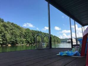 A wooden deck with metal diving steps overlooking a lake, surrounded by trees and a clear sky. - Bullwinkle Inn' private dock, hot tub, quiet water (Speedwell)