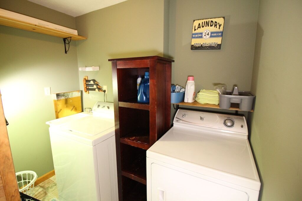 Un cuarto de lavandería con dos lavadoras, un armario de madera y un letrero de lavandería en la pared.