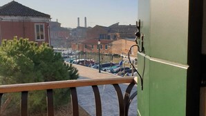 A balcony with a metal railing overlooking a marina with boats and buildings in the background.