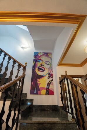 Un escalier avec une rampe, un mur orné d’une peinture colorée et un plafond doté d’un éclairage encastré.