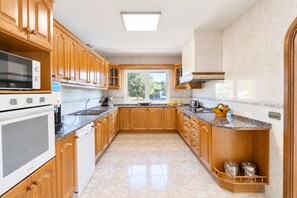 A spacious kitchen with wooden cabinets, a built-in oven, and a large window providing natural light.