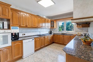 A modern kitchen with wooden cabinets, a built-in oven, a dishwasher, and a granite countertop.