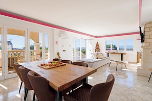 A spacious living area with a wooden dining table set for a meal, a comfortable sofa, and a view of the outdoors.