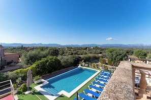 Ein Pool mit blauem Wasser, umgeben von Grünpflanzen und einem klaren Himmel.