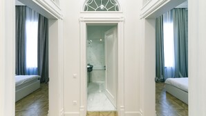 A hotel room with a large bed, a bathroom with a shower, and a view of the city through the window. - Kyiv Apartments (Kyiv)