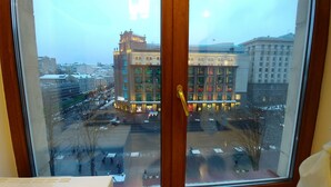 A view through a window of a building with a large glass facade, a parking lot, and a snowy street. - Kyiv Apartments (Kyiv)