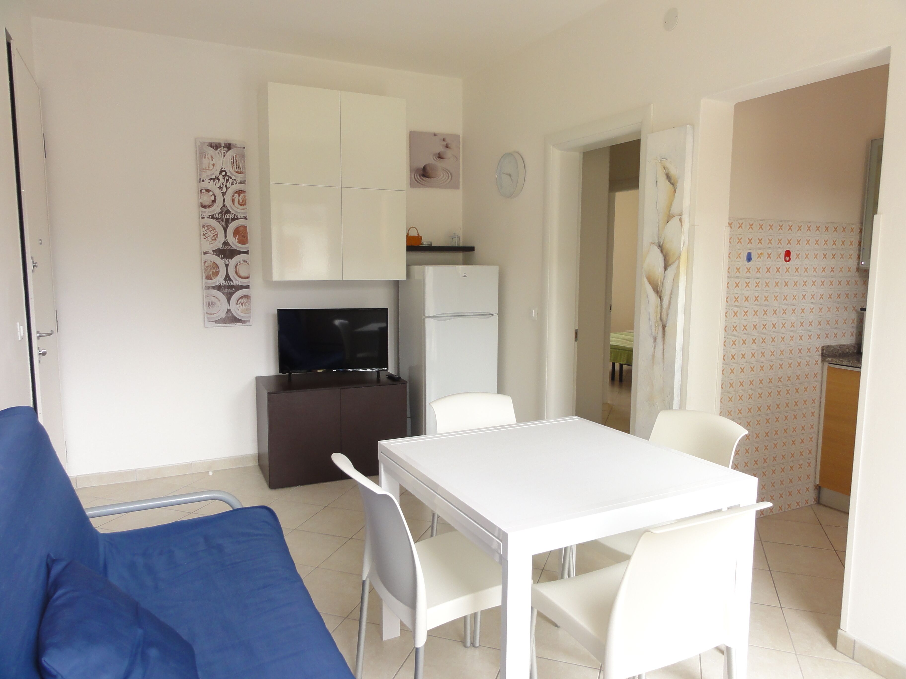 A compact living space with a kitchenette, a dining area with a table and chairs, a sofa, and a television.