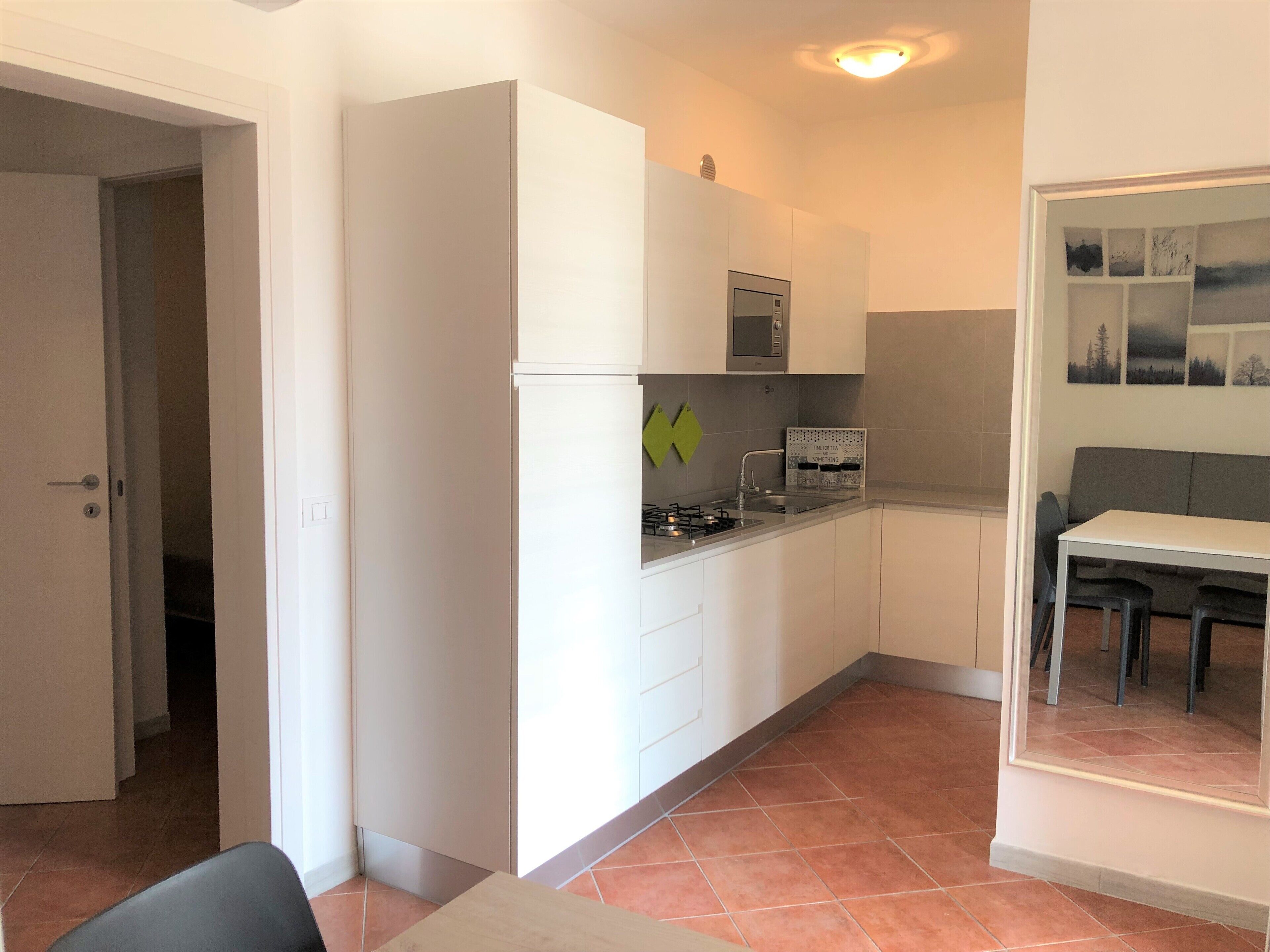 Une cuisine compacte avec des meubles blancs, une cuisinière à gaz et un petit plan de travail.
