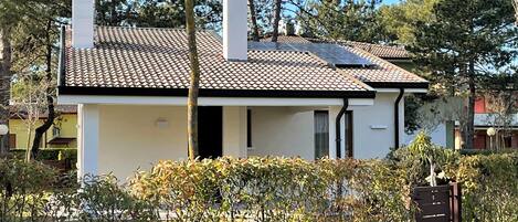 A two-story house with a tiled roof, a chimney, and a gated entrance.