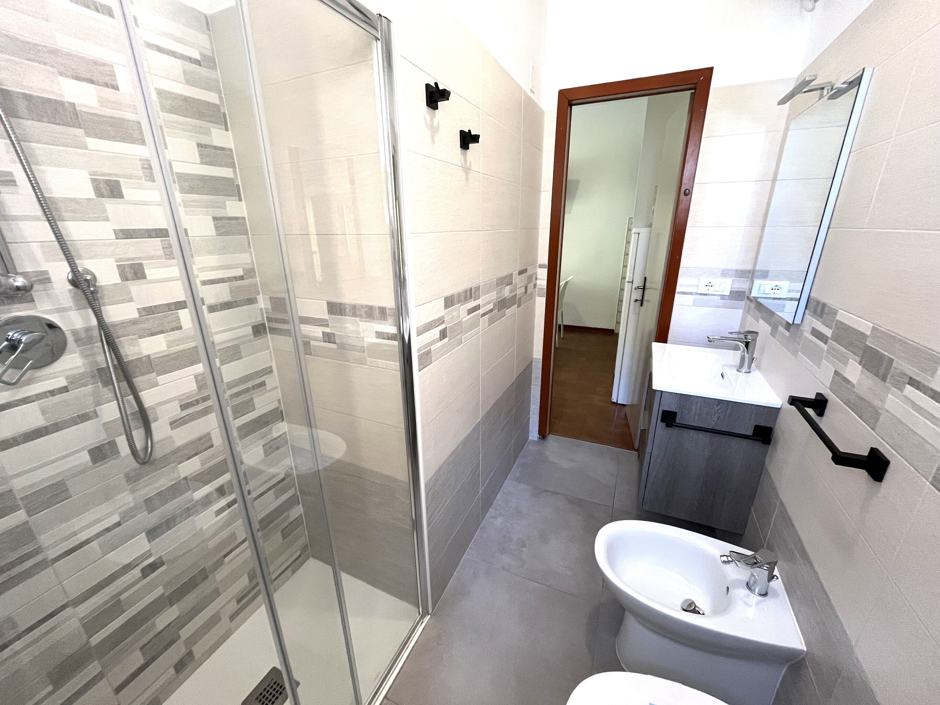 A modern bathroom with a glass-enclosed shower, a sink, and a bidet.