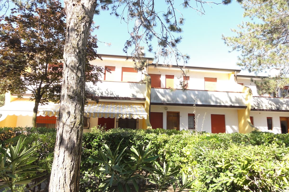 Un immeuble doté de nombreux balcons, entouré d’une végétation luxuriante et d’arbres.