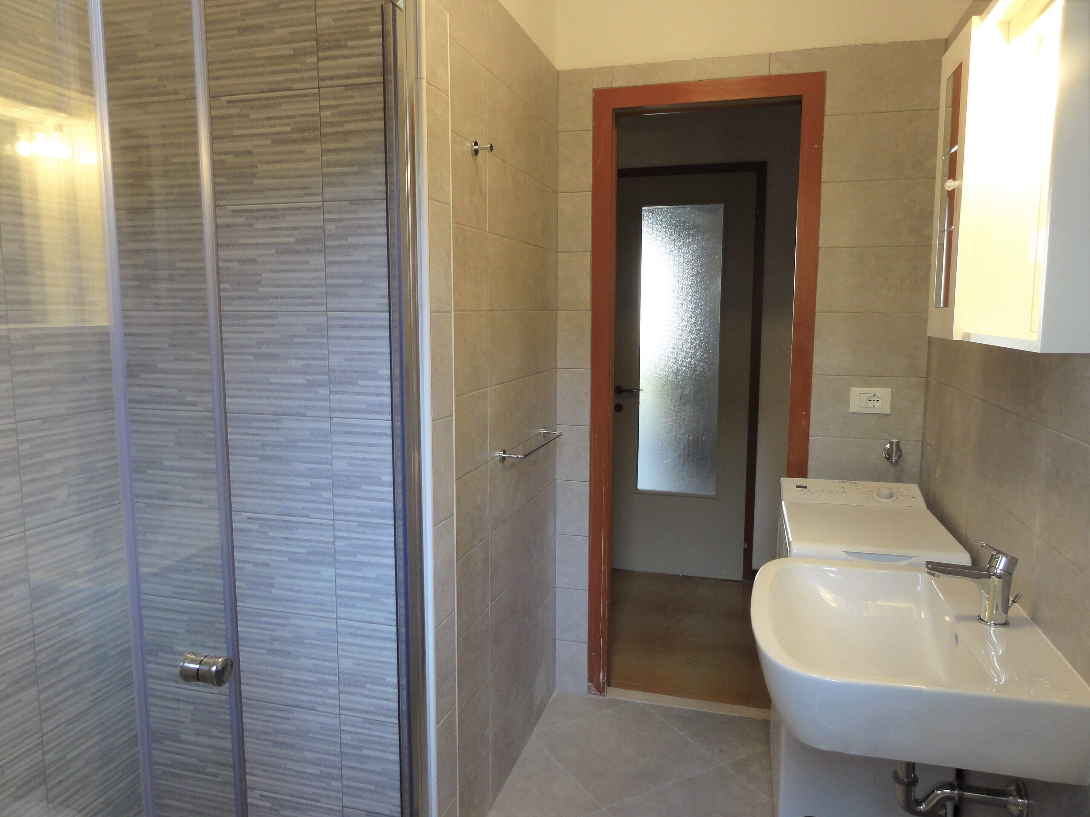 A bathroom with a shower, a sink, and a mirror.