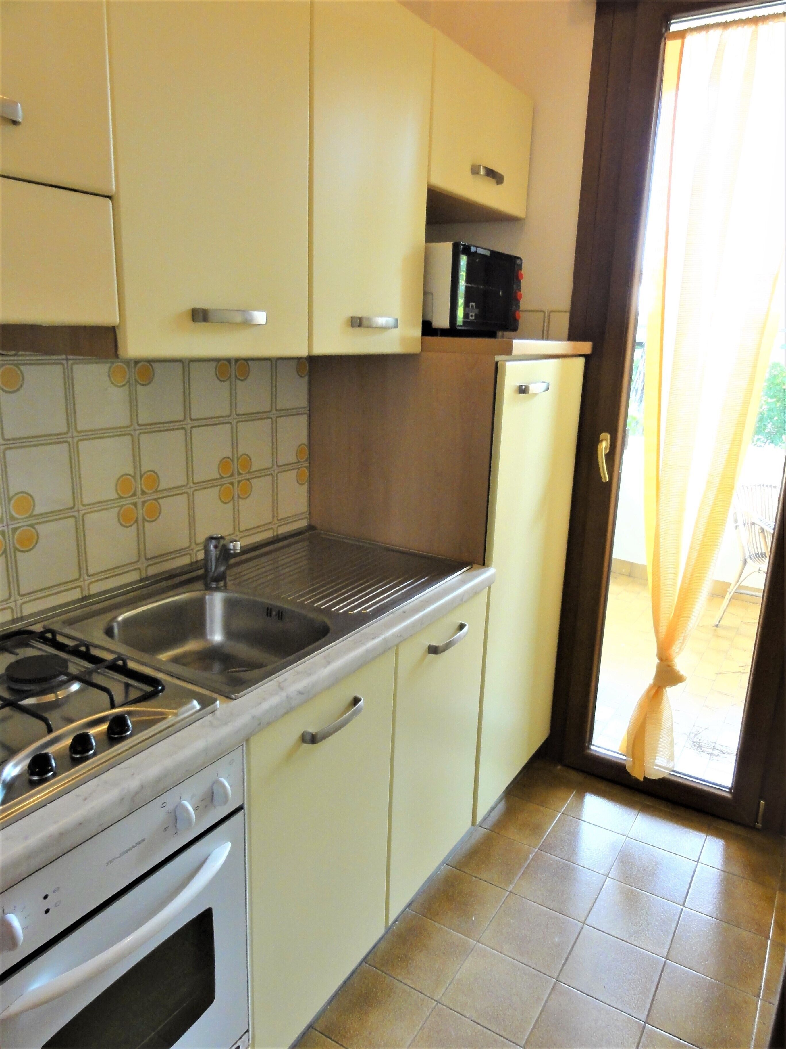 A kitchen with a stove, sink, and cabinets.