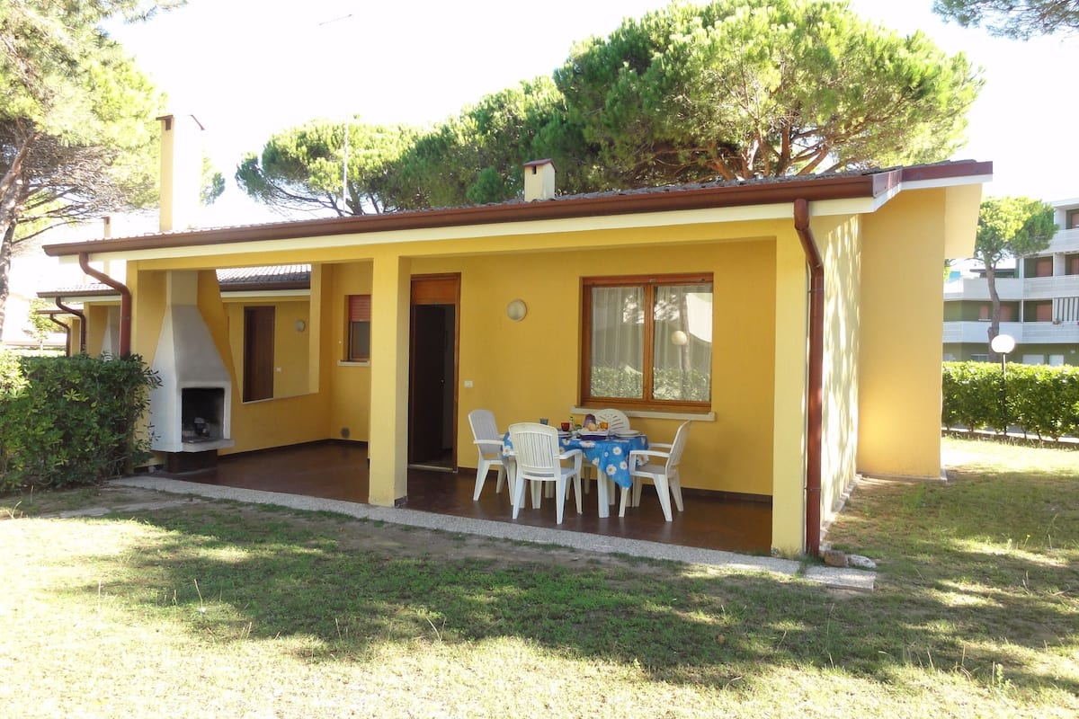 Un bâtiment jaune doté d’un patio, d’un barbecue et d’une table avec des chaises.