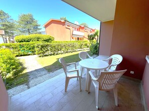 Un balcone con tavolo e sedie, vista su un edificio e un giardino curato.