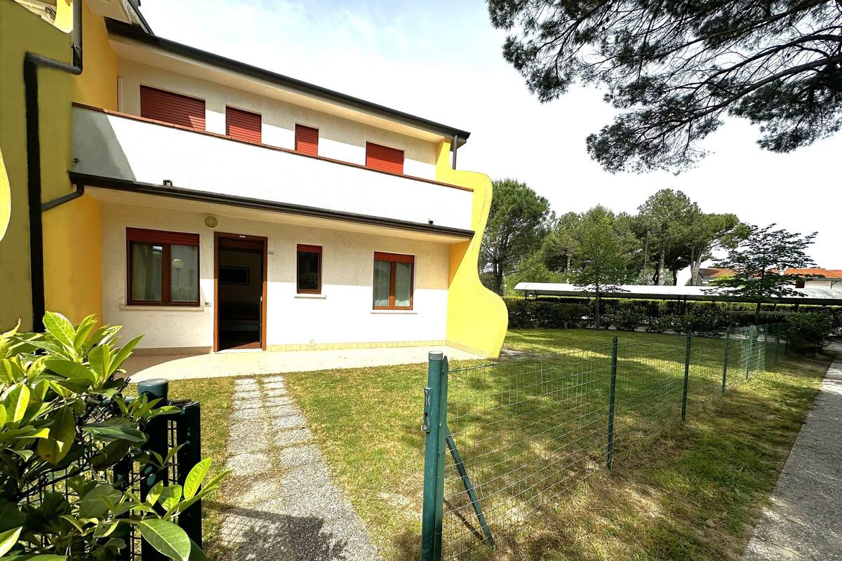 Un bâtiment jaune avec un toit plat, une porte et trois fenêtres.