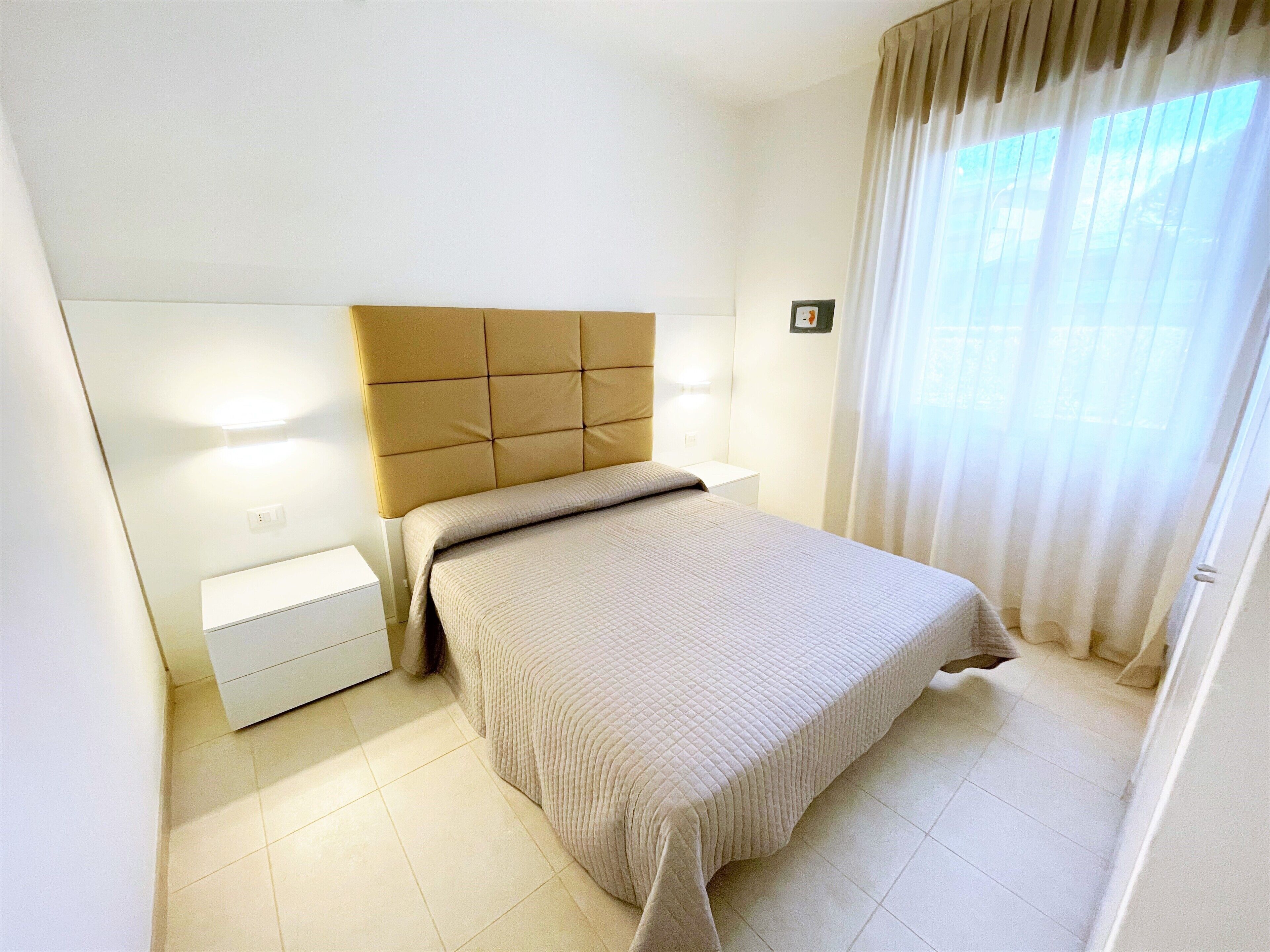 Quarto bem arrumado com uma cama, uma mesa de cabeceira e um criado-mudo.