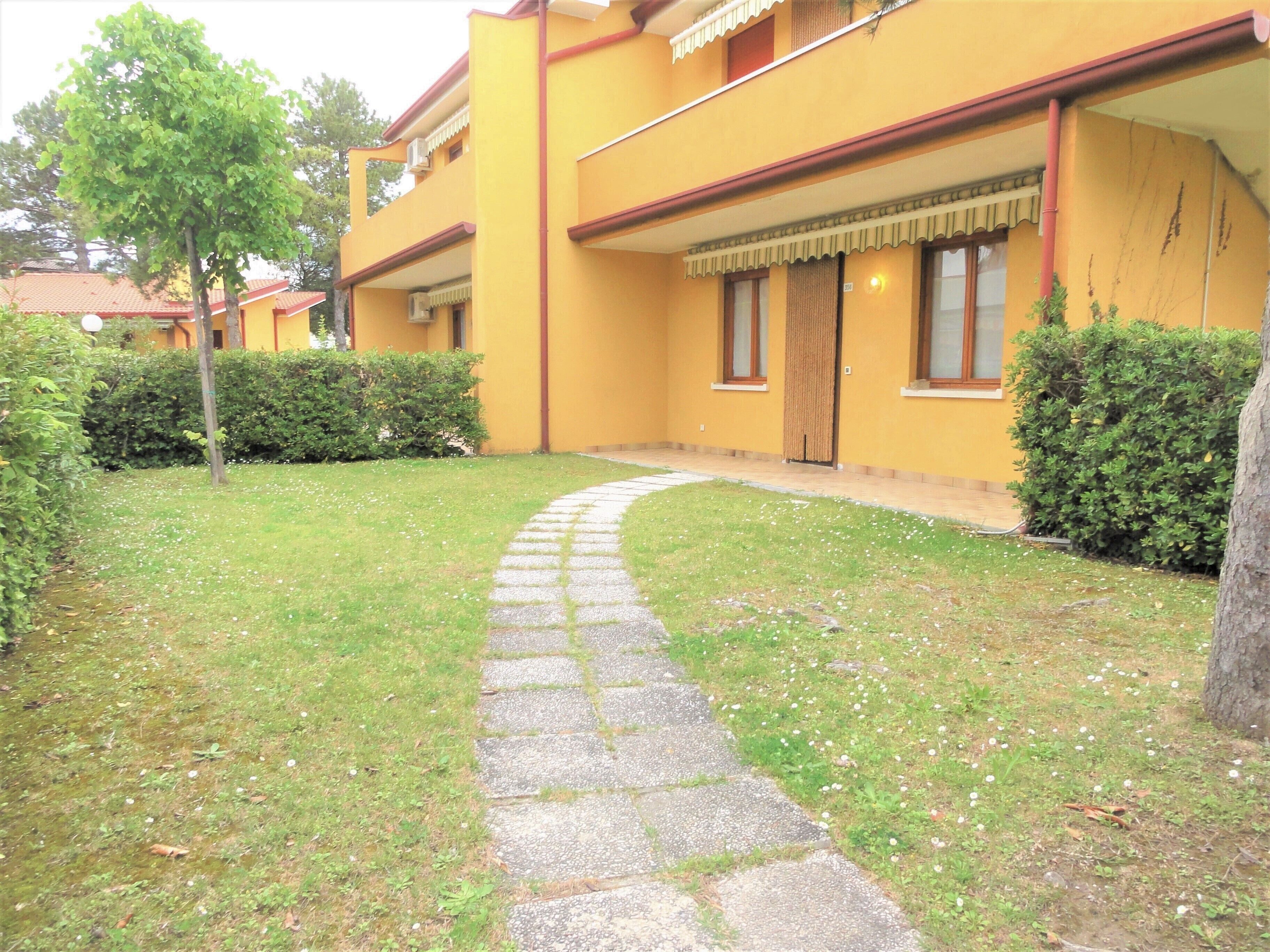 A yellow building with a stone pathway leading to the entrance.