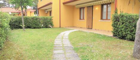 A yellow building with a stone pathway leading to the entrance.