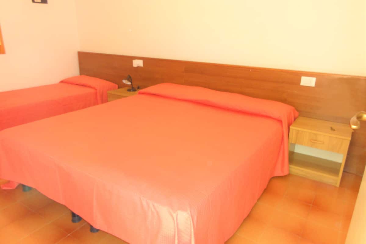 Une chambre avec deux lits, chacun doté d’une tête de lit en bois et d’une table de chevet.