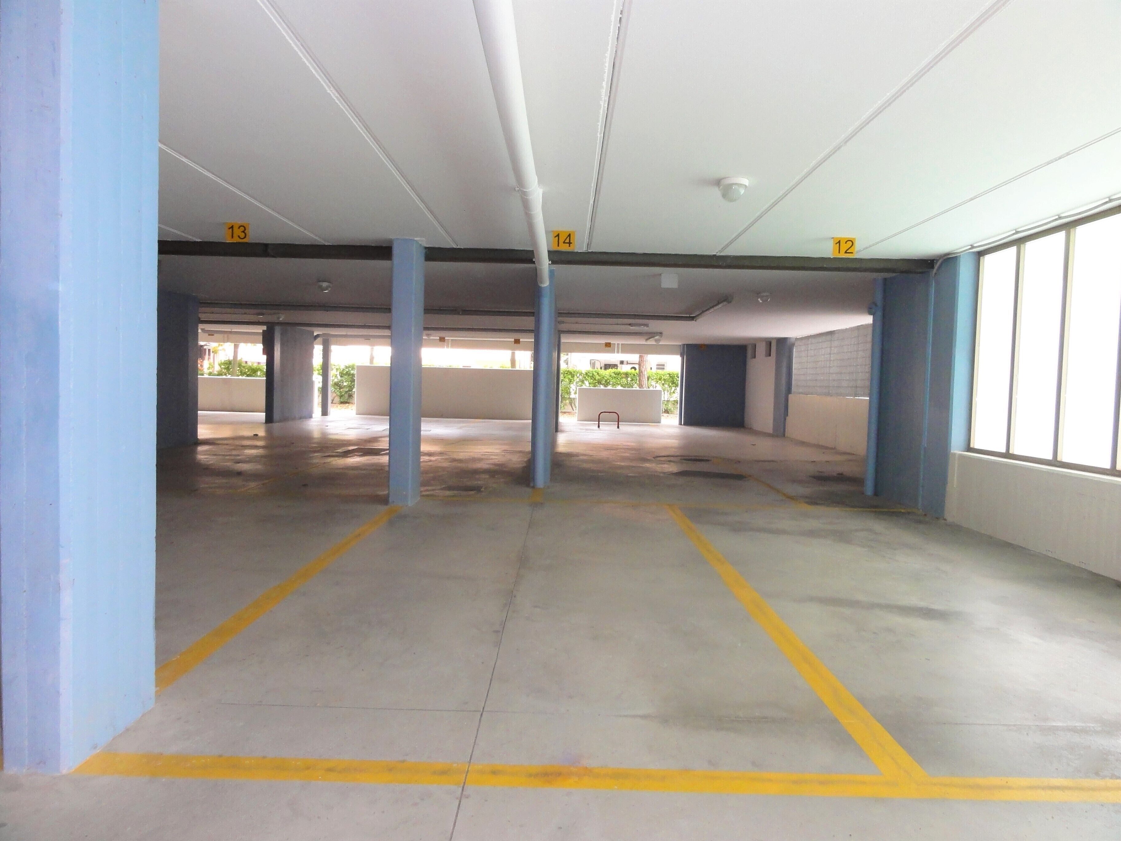 An indoor parking garage with concrete floors and blue pillars.
