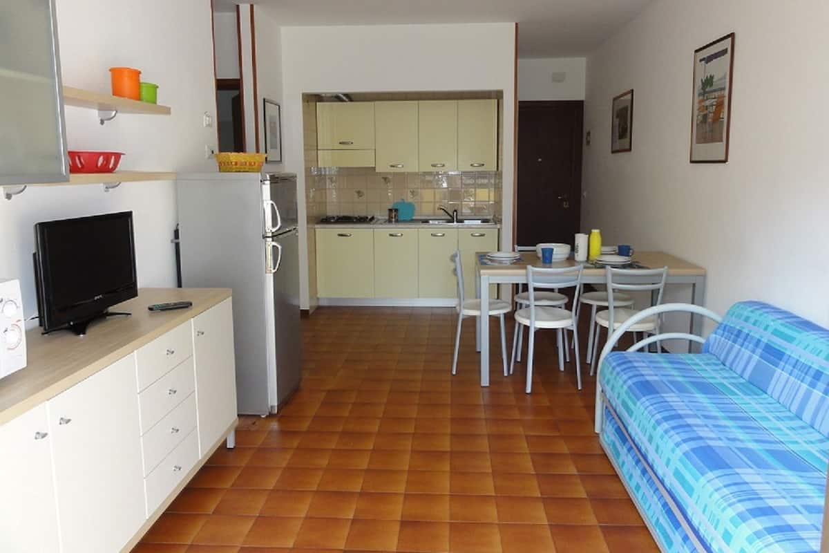 Een knus woongedeelte met kitchenette, een eethoek en een bank.